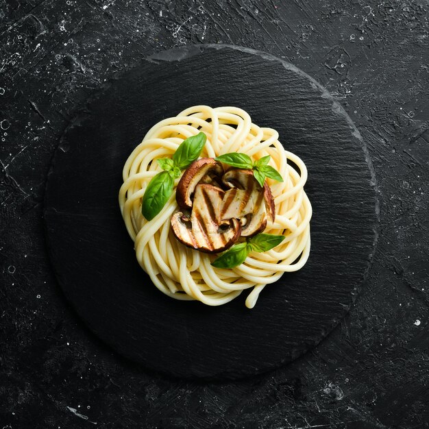 Pâtes spaghetti aux champignons et basilic dans une assiette en pierre noire Cuisine italienne Vue de dessus Espace libre pour le texte