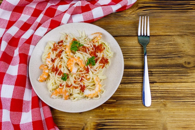 Pâtes spaghetti aux crevettes sauce tomate et persil sur table en bois Vue de dessus