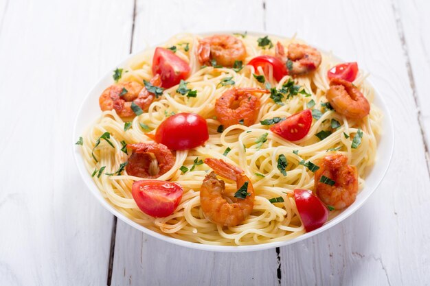 Photo pâtes spaghetti aux crevettes, tomates et persil fond de fruits de mer