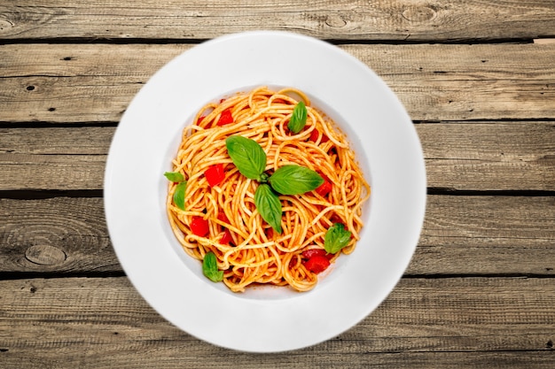 Pâtes spaghetti aux tomates et persil sur table.