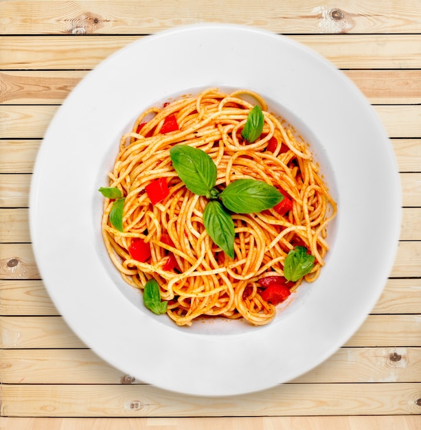 Pâtes spaghetti aux tomates et persil sur table.