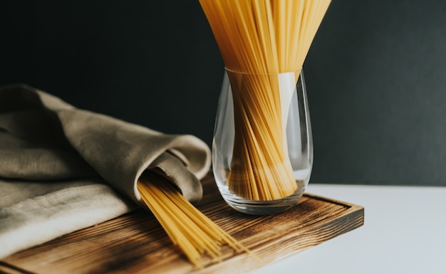 Pâtes spaghetti de blé en verre sur une planche de bois