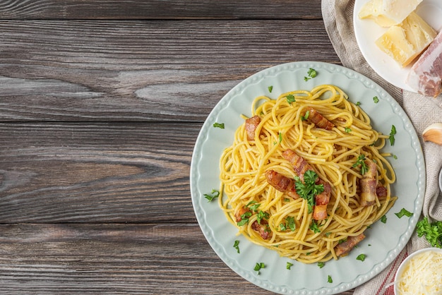 Pâtes spaghetti carbonara avec pancetta bacon oeuf parmesan fromage sur fond de bois cuisine italienne vue de dessus