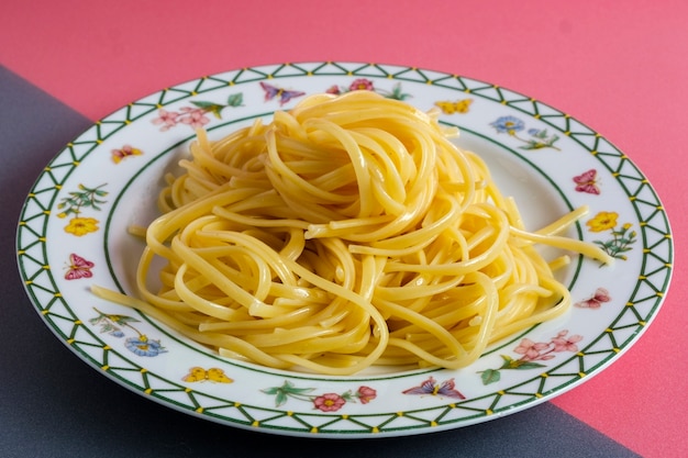 Pâtes spaghetti nature isolée sur rose et gris