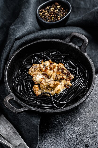 Pâtes spaghetti noires au saumon en sauce à la crème. Fond noir. Vue de dessus