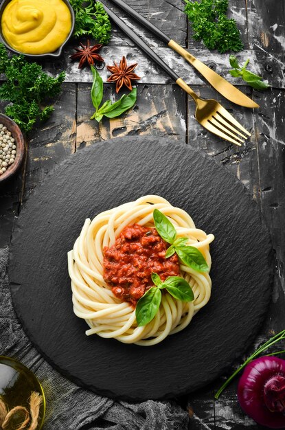 Pâtes spaghetti à la sauce bolognaise et basilic dans une assiette en pierre noire. Nourriture italienne. Vue de dessus. Espace libre pour le texte.