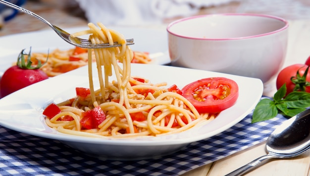 Pâtes spaghettis et sauce tomate sur fond de bois