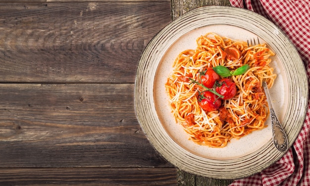 Pâtes Spashetti à la sauce tomate et tomates cerises au four sur bois rustique.