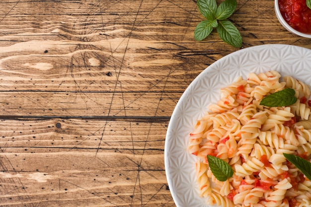 Pâtes en spirale mélangées avec des tomates cerises et de la sauce tomate sur une assiette.