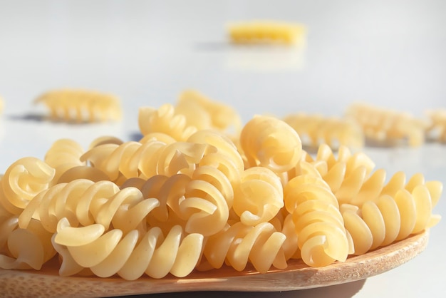 Les Pâtes En Spirale Se Trouvent Dans Une Cuillère En Bois Sur Un Tableau  Blanc Le Concept De Cuisine Restauration