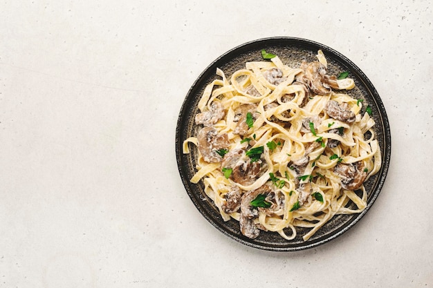 Pâtes tagliatelles aux champignons avec fromage parmesan et sauce à la crème sur fond blanc vue de dessus Pâtes italiennes préparées avec champignon sur plaque grise