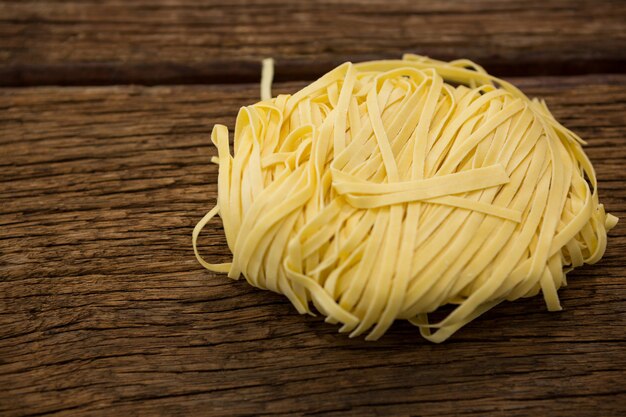 Pâtes tagliatelles crues sur une surface en bois