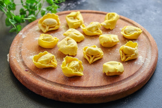 Pâtes tortellini raviolis farcis sur planche de bois