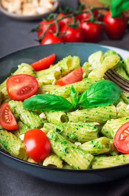 Pâtes tortiglioni maison fraîche avec sauce pesto vegan noix de cajou et tomates cerises sur béton gris Gros plan