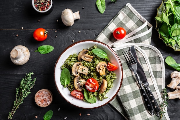 Pâtes vertes végétaliennes végétariennes aux épinards, champignons champignon, tomates cerises.