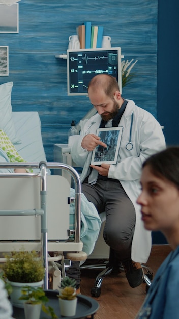 Patient âgé malade regardant la tablette avec le rayon X d'ostéopathie