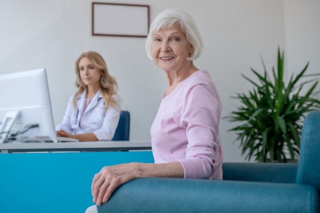 Patient âgé souriant assis dans le bureau du médecin et à la satisfaction