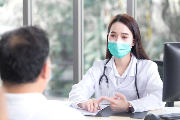 Un patient asiatique âgé consulte une femme médecin professionnelle au sujet de ses symptômes pendant qu'il est médecin