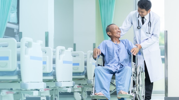 Patient asiatique en fauteuil roulant assis dans le couloir de l&#39;hôpital avec un médecin asiatique.