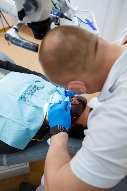 Patient à bouche ouverte allongé dans le fauteuil du dentiste pendant que le dentiste tient un instrument dentaire. Soins dentaires dans une clinique dentaire moderne. mise au point sélective