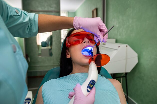 Patient avec la bouche ouverte assis dans une chaise de dentiste dans des lunettes de protection