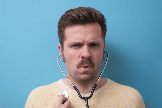 Patient caucasien avec moustache écoutant son coeur battre en studio de maîtrise de soi