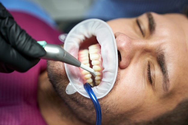 Photo patient de clinique dentaire avec les yeux fermés et la digue dentaire