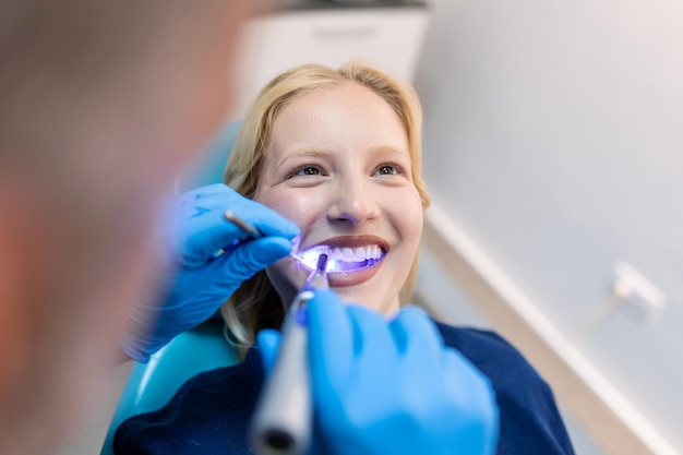 Patient dans la clinique dentaire Lampe UV de blanchiment des dents avec composition photopolymère Jeune femme pendant la procédure de blanchiment des dents avec durcissement de la lumière UV au cabinet du dentiste