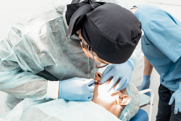 Patient et dentiste pendant l'opération de pose d'implant. Fonctionnement réel. Extraction dentaire, implants. Santé Équiper un poste de médecin. Dentisterie