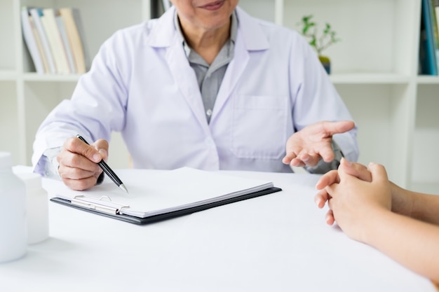 patient écoutant attentivement un médecin masculin expliquant les symptômes du patient ou posant une question alors qu&#39;ils discutent de la paperasserie ensemble dans une consultation