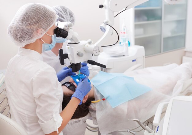 Patient d'examen de dentiste professionnel avec microscope au bureau