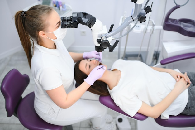 Patient d'examen de dentiste professionnel avec microscope au bureau