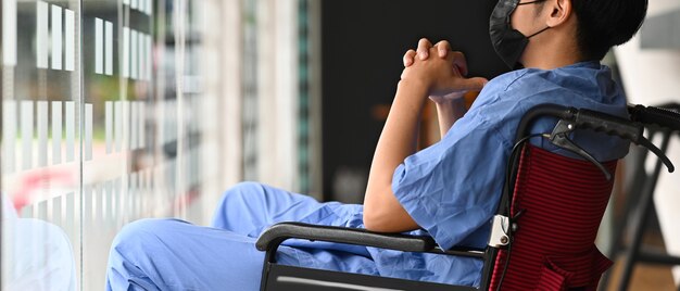 Patient homme assis sur un fauteuil roulant dans une chambre d'hôpital se sentant seul et déprimé.