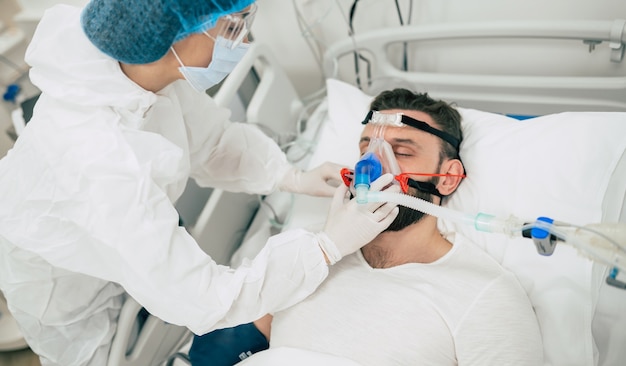 Patient infecté par le coronavirus Covid-19 dans une salle de quarantaine de l'hôpital avec des médecins en tenue de protection pendant qu'ils le soignent