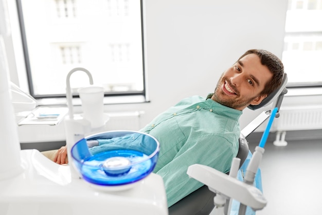 un patient mâle heureux et souriant à la clinique dentaire