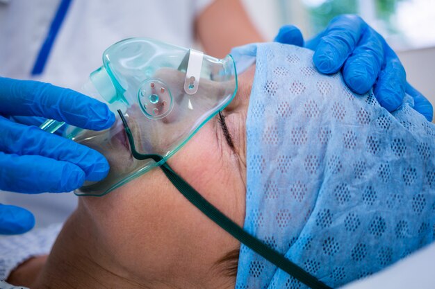 Patient portant un masque à oxygène allongé sur un lit d'hôpital