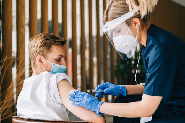 Un patient de race blanche se fait vacciner contre le coronavirus recevant le vaccin covid. Injection intramusculaire lors d'un rendez-vous chez le médecin à l'hôpital. Vaccination Covid-19.