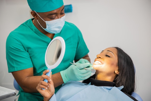 Le patient regarde ses dents avec le miroir lors d'une visite chez le dentiste