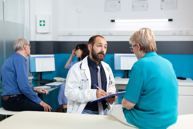 Patient retraité discutant avec un médecin de l'ostéopathie et des blessures physiques lors d'une consultation de soins de santé. Médecin et femme âgée ayant une conversation pour faire de l'exercice pour la récupération des os.