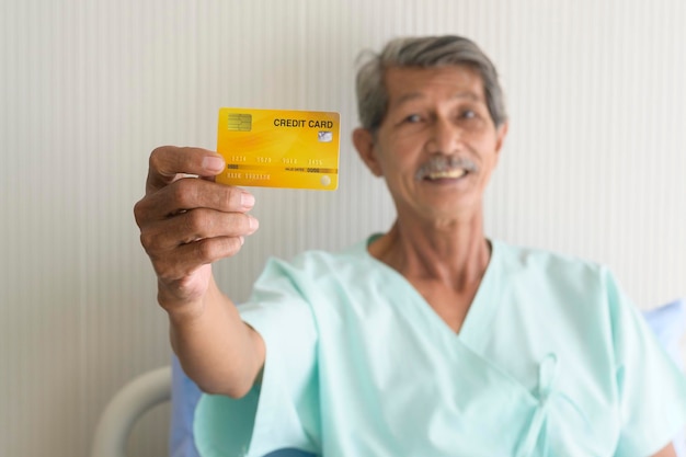 Un patient senior asiatique montre une carte de crédit à l'hôpital