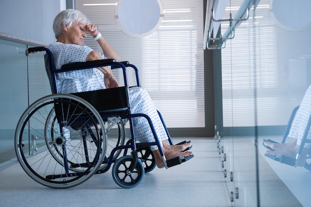 Patient senior handicapé en fauteuil roulant dans le passage de l'hôpital