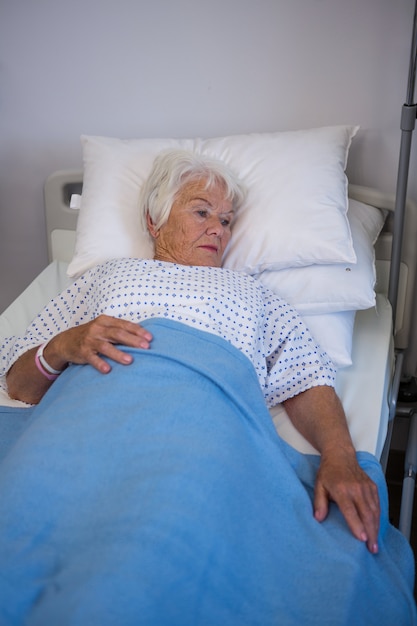 Patient senior réfléchi allongé sur le lit