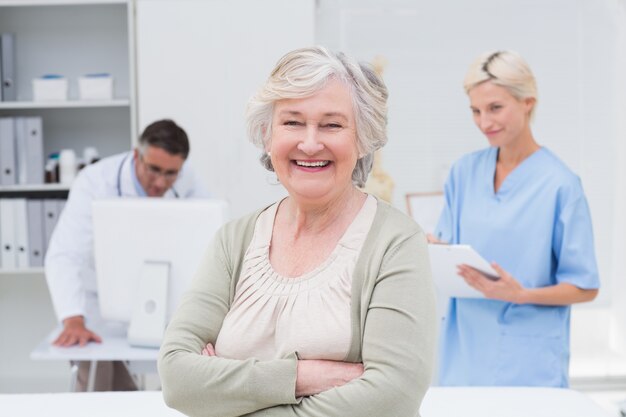 Patient souriant alors que le médecin et l&#39;infirmière travaillent en arrière-plan