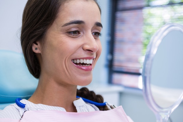 Patient souriant tout en regardant le miroir en clinique dentaire