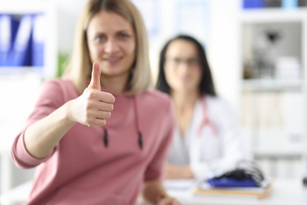 Le patient tient le pouce vers le haut dans un cabinet médical le médecin s'assoit pour un examen médical