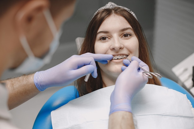 Patiente avec des accolades examinant l'inspection dentaire au bureau du dentiste. Femme en vêtements blancs