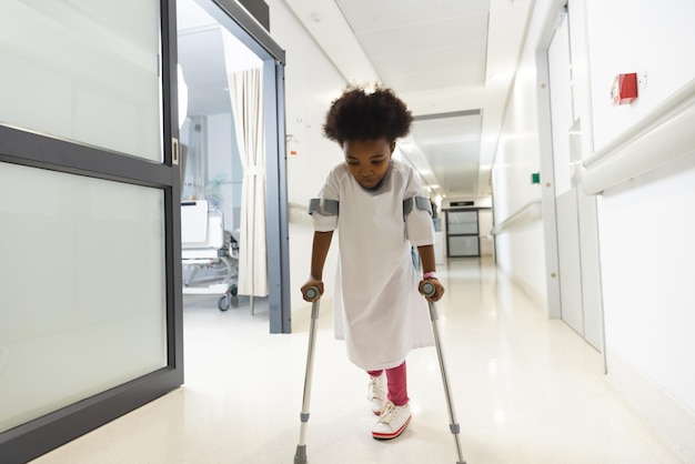 Une patiente afro-américaine marche avec des béquilles dans le couloir de l'hôpital. Hôpital, handicap, enfance, médecine et soins de santé, inchangés.