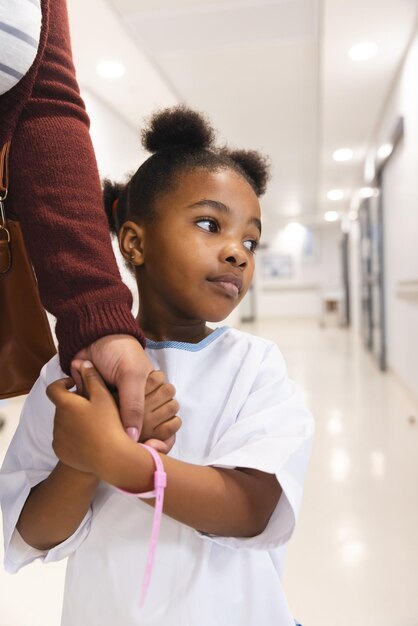 Photo une patiente afro-américaine et sa mère se tenant par la main dans le couloir de l'hôpital. hôpital, maternité, famille, médecine et soins, inchangés.