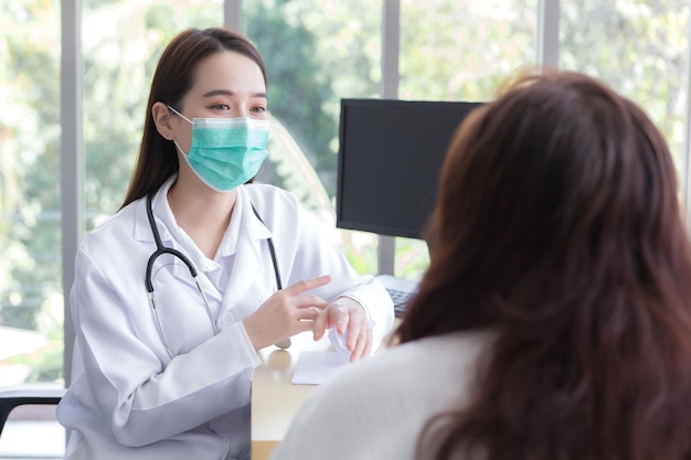 Une patiente âgée asiatique est vérifiée par une femme médecin tandis que les deux portent un masque médical