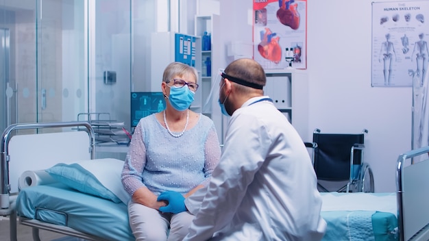 Une patiente âgée inquiète dans une clinique ou un hôpital moderne se consolant d'un médecin qui porte des vêtements de protection et des gants médicaux. Pandémie mondiale de coronavirus covid-19 pandémie de soins de santé